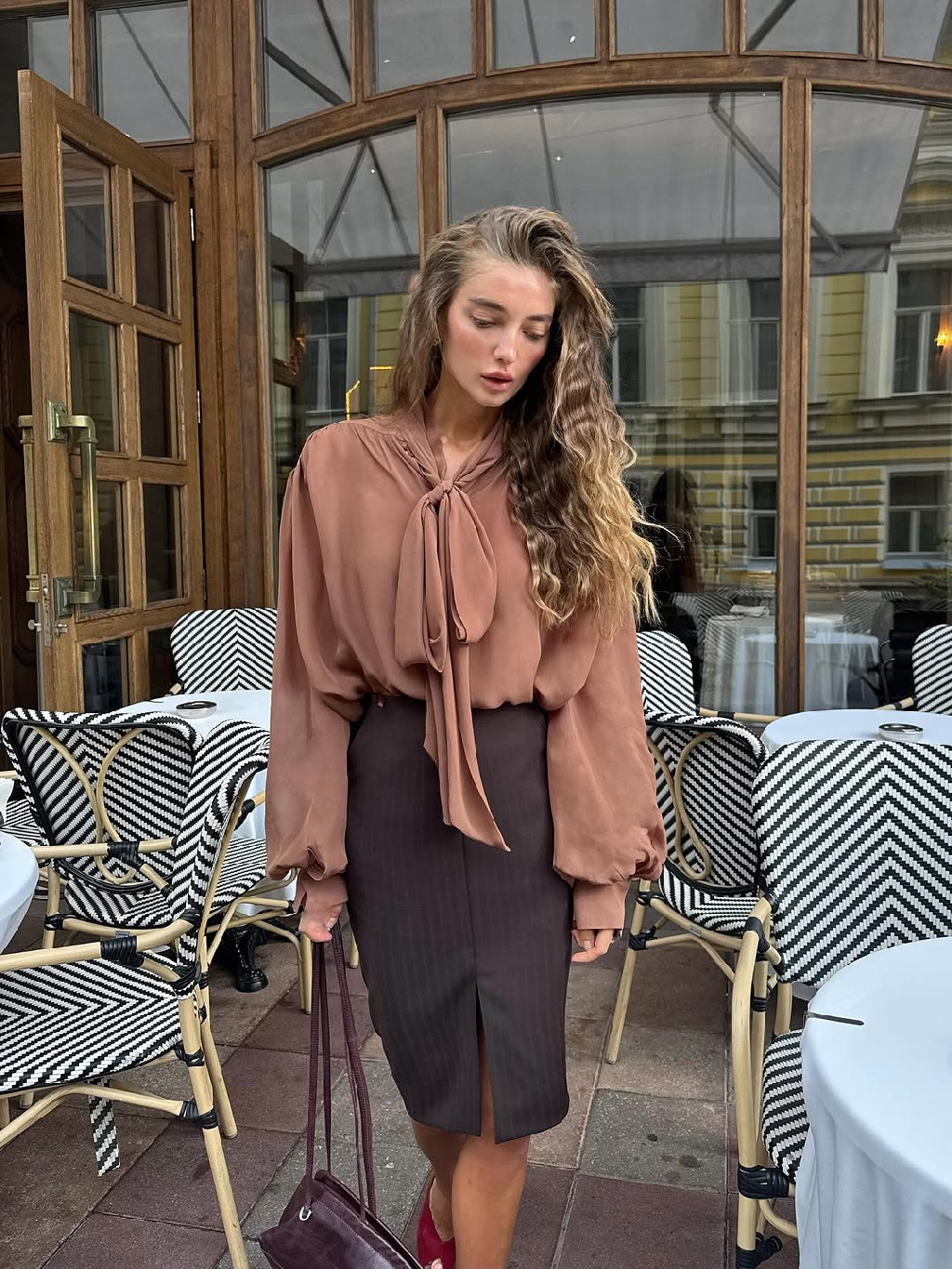 Образ от Лены Шевченко в теплой гамме - бронзовая блуза и шоколадная юбка создают гармонию насыщенных оттенков.

Воздушный шифон добавляет образу мягкости и движения, а строгий силуэт юбки из вирджинской шерсти формирует собранность. Вместе они складываются в настроение, где глубина цвета соединяется с элегантной простотой линий.